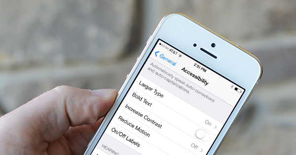 A stock photo of a hand holding an iPhone, which is open to the accessibility settings page.